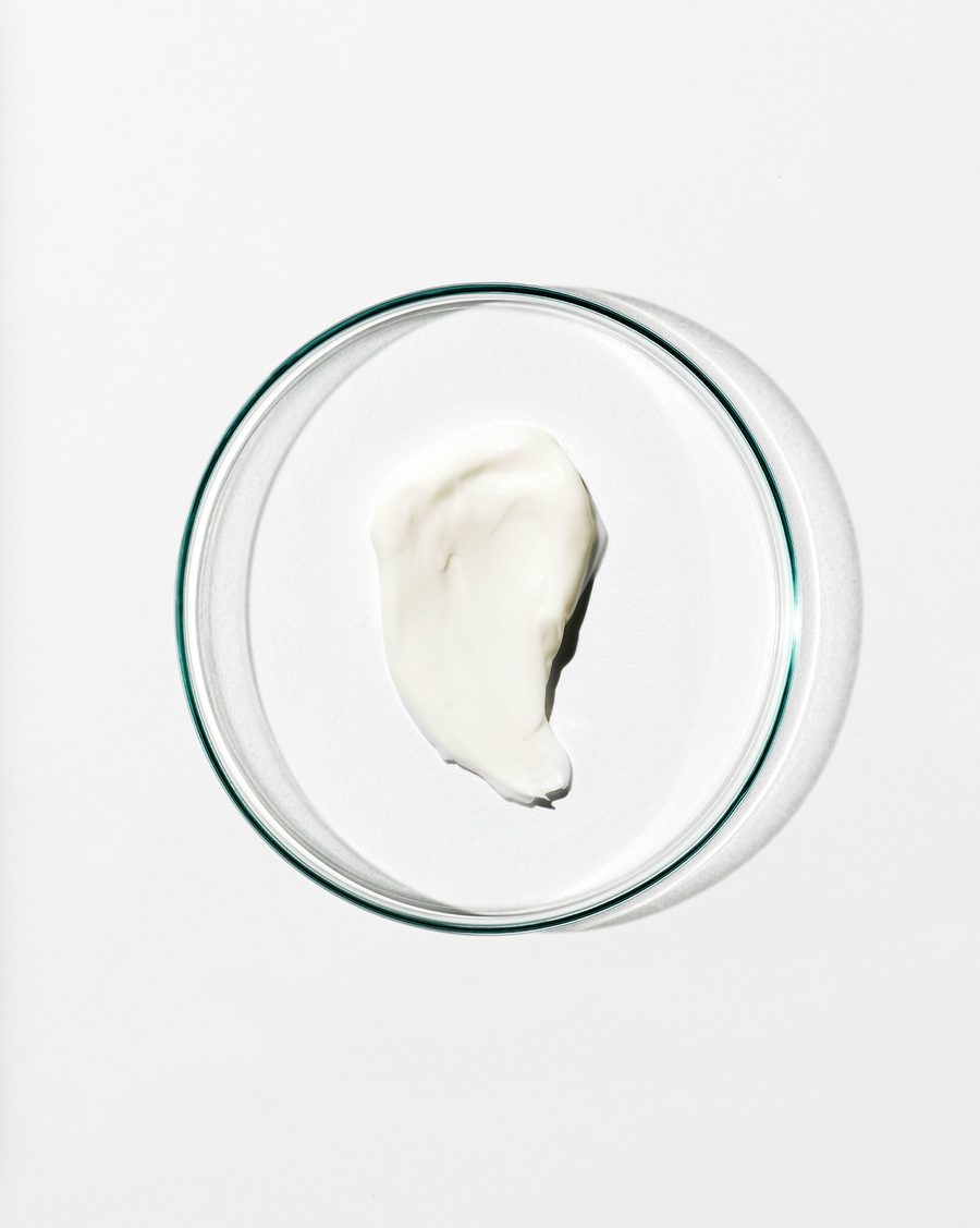 Glass bowl with swatch of moisturiser on a white background