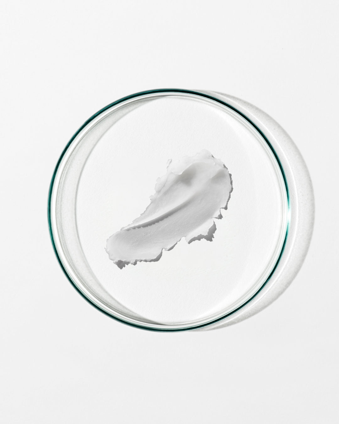White cream in a clear glass bowl on a white background