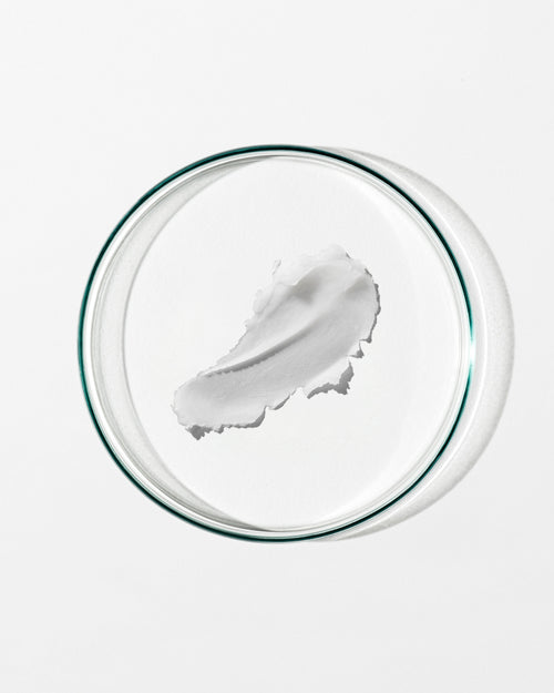 White cream in a clear glass bowl on a white background