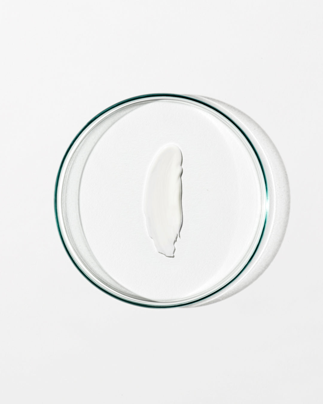 Clear glass bowl with cream on a white background