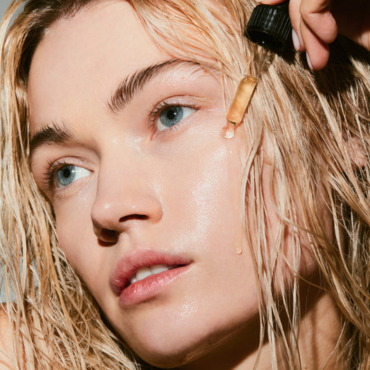 Close-up of a person applying a dropper of Skin Renewal Serum to their face.