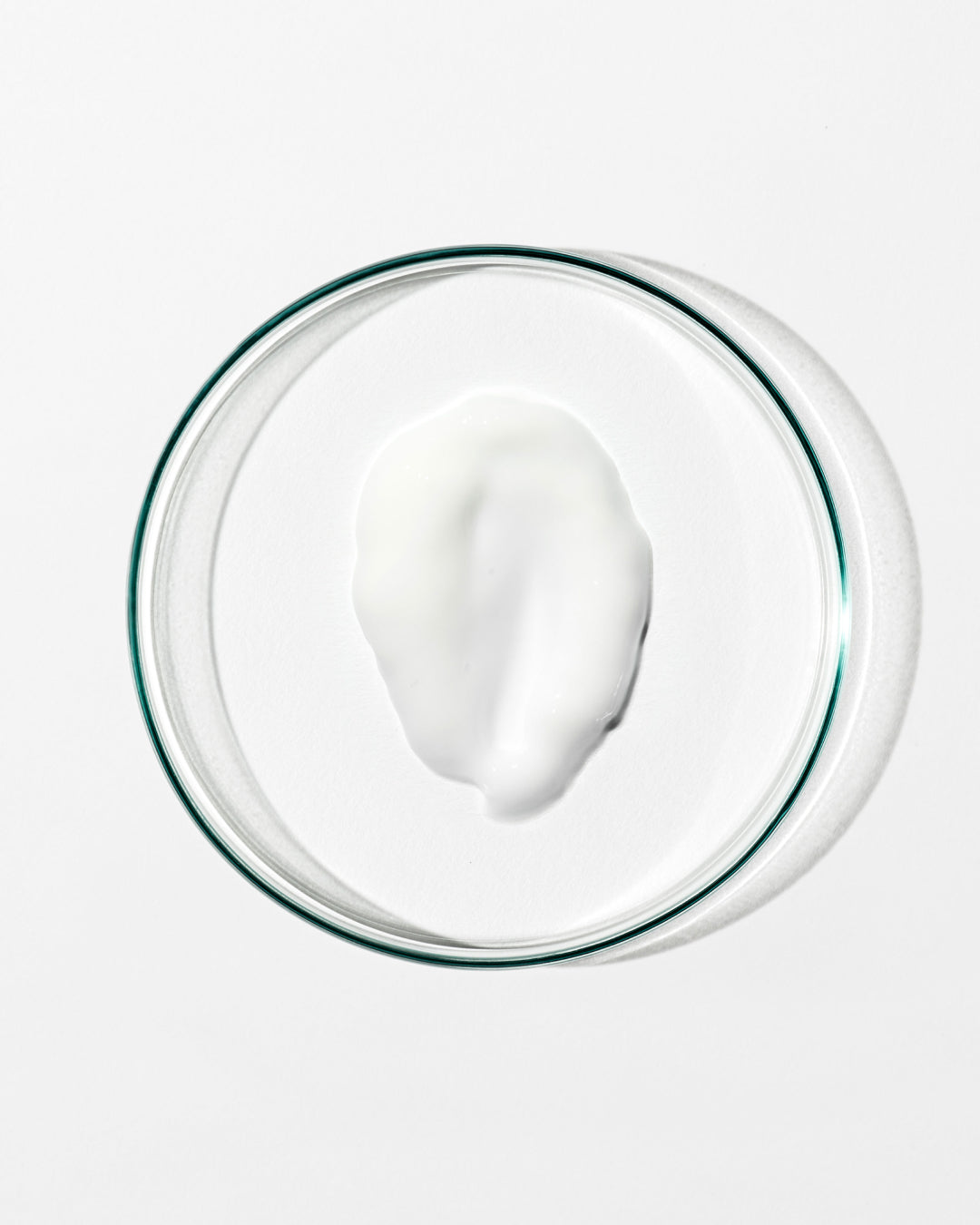 White cream in a clear glass bowl on a white background