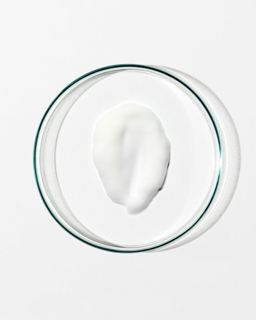 White cream in a clear glass bowl on a white background