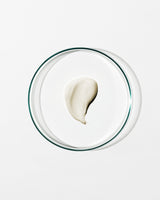 Glass bowl with a single scoop of white cream on a light gray background