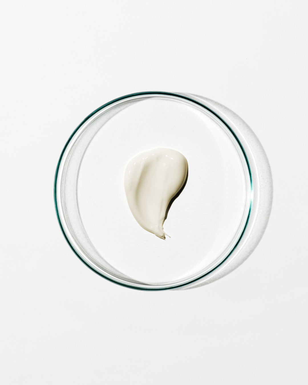 Glass bowl with a single scoop of white cream on a light gray background