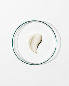 Glass bowl with a single scoop of white cream on a light gray background