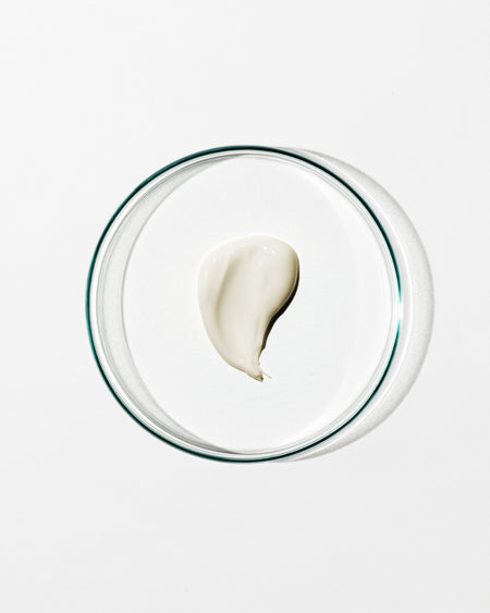 Glass bowl with a single scoop of white cream on a light gray background