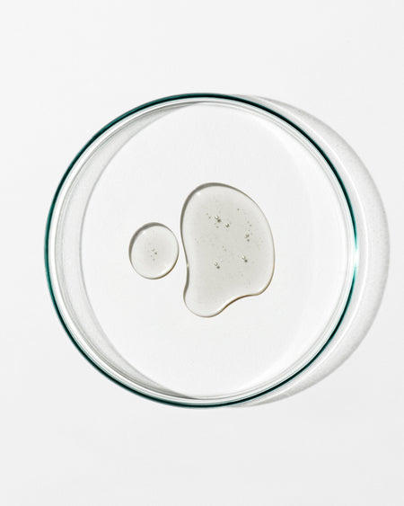 Clear glass lid with a small amount of white substance on a white background