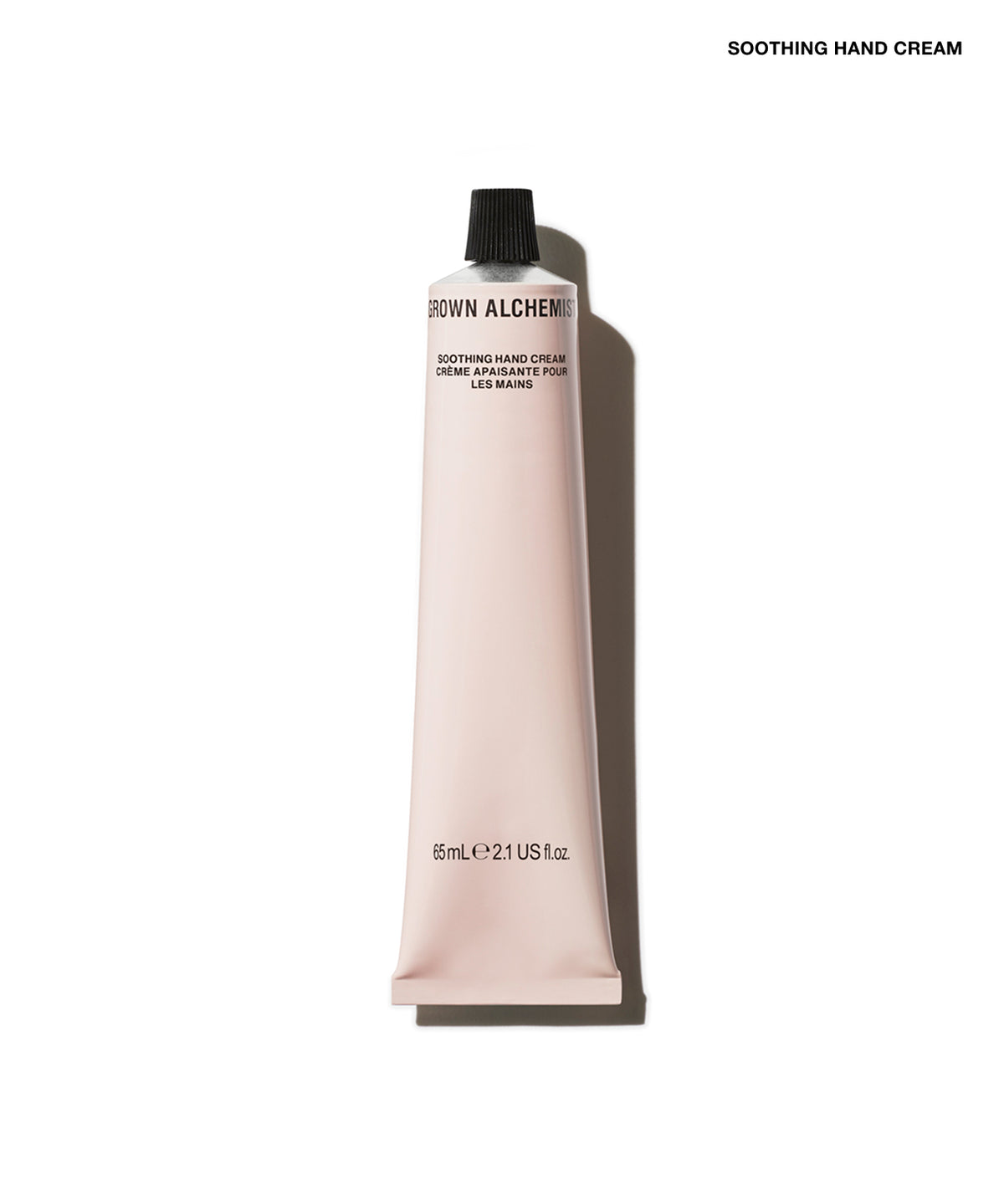 A squeeze tube of Grown Alchemist Soothing Hand Cream in a pale pink color with a black cap, shown on a white background with a soft shadow.