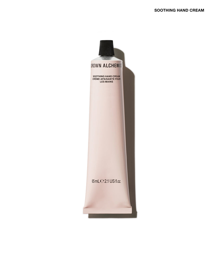 A squeeze tube of Grown Alchemist Soothing Hand Cream in a pale pink color with a black cap, shown on a white background with a soft shadow.