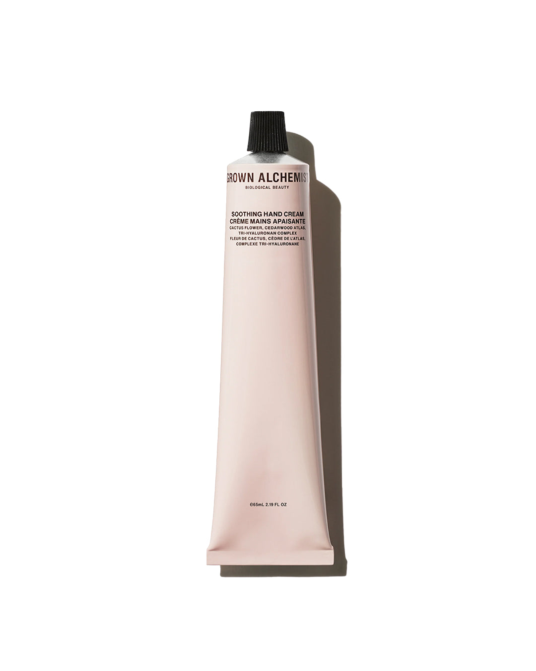 Pink tube of Brown Alchemist hand cream on a white background