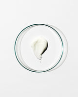 Glass bowl with a small amount of white cream on a white background