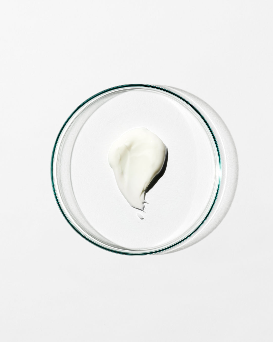 Glass bowl with a small amount of white cream on a white background