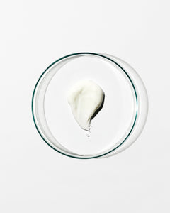 Glass bowl with a small amount of white cream on a white background