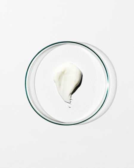 Glass bowl with a small amount of white cream on a white background