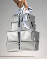Four parcels wrapped in silver paper, bound by Grown Alchemist ribbon against a light background