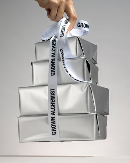 Four parcels wrapped in silver paper, bound by Grown Alchemist ribbon against a light background