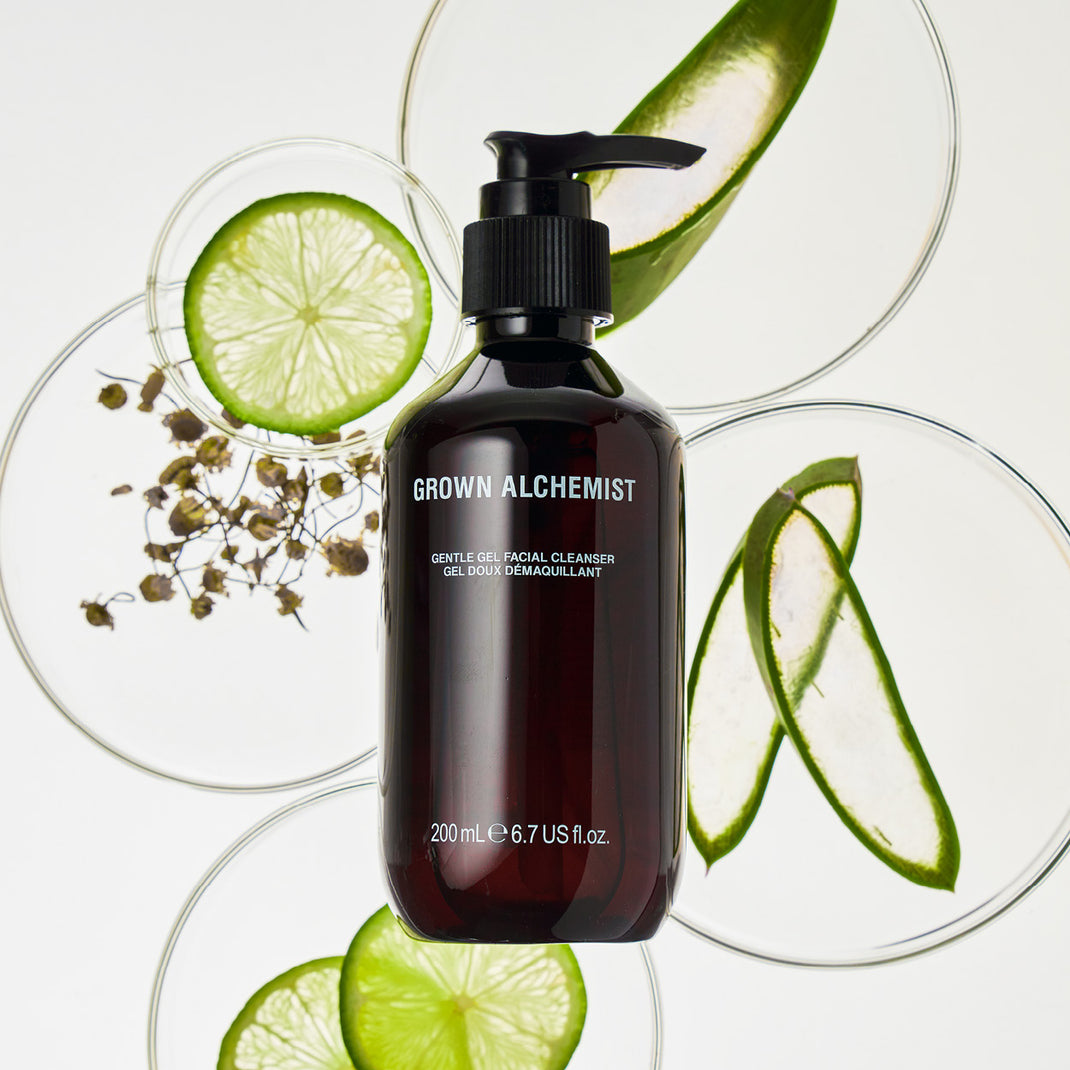 Grown Alchemist facial cleanser bottle with lime slices and aloe vera on a white background