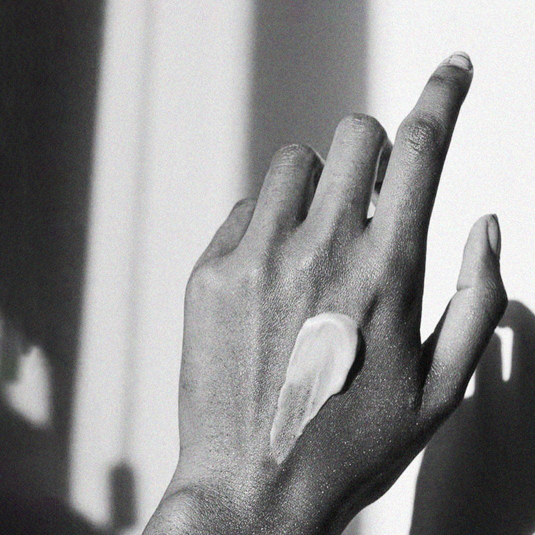 Black and white photo of a hand with a dollop of cream on the back
