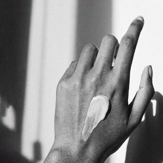 Black and white photo of a hand with a dollop of cream on the back
